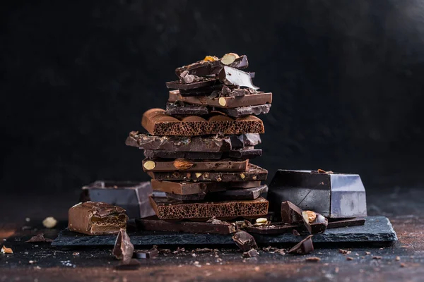 Bar of Chocolate tower pieces. Hazelnut and almond dark chunks of broken chocolate. Sweet food photo concept.