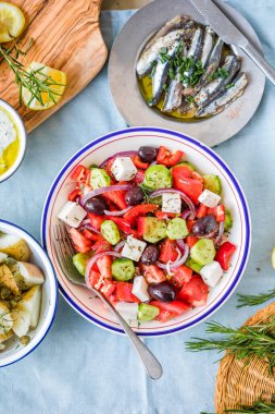 Yunan yemek masası sahnesi, üst manzara. Yunan salatası, salatalık sosu, Tzatziki, ançüez filetosu, limon patatesi gibi çeşitli ürünler..