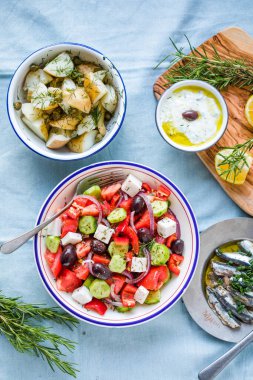 Yunan yemek masası sahnesi, üst manzara. Yunan salatası, salatalık sosu, Tzatziki, ançüez filetosu, limon patatesi gibi çeşitli ürünler..
