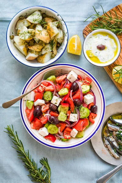 希腊餐桌场景 种类繁多的项目 包括希腊沙拉 黄瓜蘸Tzatziki 凤尾鱼片 柠檬土豆 — 图库照片