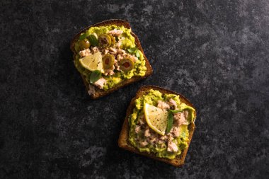 Lezzetli ton balıklı tost. İtalyan bruschetta sandviçi, konserve ton balığı, avokado, zeytin, lezzetli kahvaltı veya atıştırmalık. Üst görünüm.