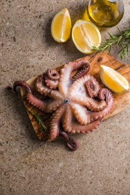 Tahtada servis edilen doğranmış bitkilerle pişirilmiş ahtapot.