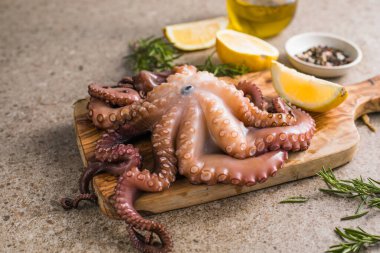 Tahtada servis edilen doğranmış bitkilerle pişirilmiş ahtapot.