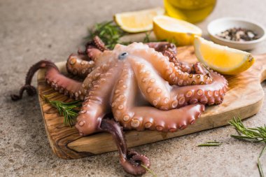 Tahtada servis edilen doğranmış bitkilerle pişirilmiş ahtapot.