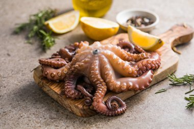 Tahtada servis edilen doğranmış bitkilerle pişirilmiş ahtapot.