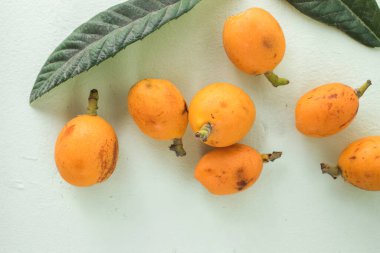 Olgun medlar meyve, Eriobotrya japonica ve ahşap masada yeşil Medlar yapraklar. Üst görünüm