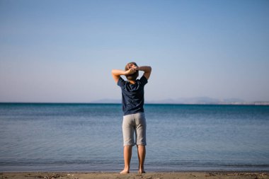 Çocuk yaz tatilinde plajda oynuyor. Doğadaki çocuklar, deniz suyunda akan kumlar ve mavilikler..