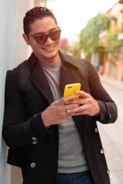 Adam sokakta cep telefonuyla yürüyor.