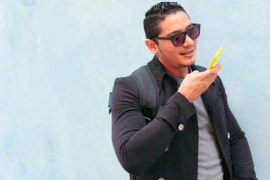 Sokaktaki genç adam cep telefonuyla sesli mesaj yolluyor.