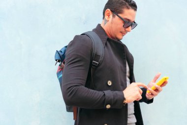 Sokaktaki yakışıklı genç adam cep telefonu kullanıyor.