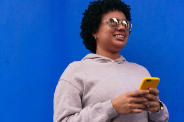 Gözlüklü bir kadın akıllı telefonuyla mesajlaşıyor.