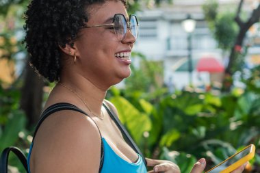 Parkta yürüyen, sırt çantası taşıyan, cep telefonu kullanan bir kız.