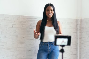 Afrikalı kadın kendini evinde filme çekiyor. Çekim için tripodun üzerindeki kamerayı kullanıyor..