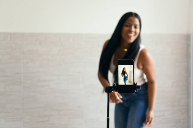 Afrikalı bir kadın telefonuyla video kaydediyor, dans ediyor. Telefon ekranına odaklan..