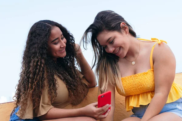 Две Молодые Женщины Сидят Городской Улице Смотрят Мобильный Телефон Разговаривают — стоковое фото