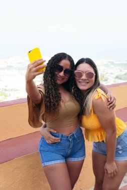 Güzel kız arkadaşlar cep telefonu kullanıyor ve gülüyorlar. Sokakta cep telefonuyla dolaşan arkadaşlar..