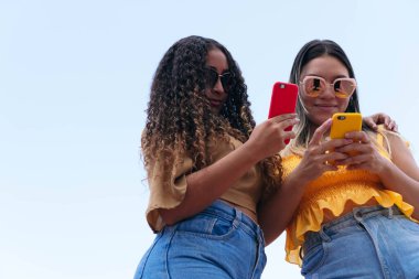 Latin arkadaşlar sokakta cep telefonuyla yürüyor..