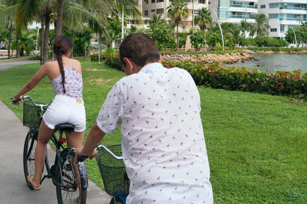 Family riding bicycles in the city park.