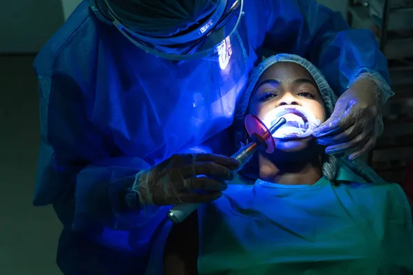 在牙科医生处接受牙齿美白治疗的年轻女性 — 图库照片