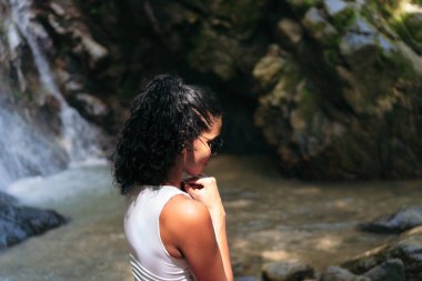 Şelalenin yanında duran genç bir kadın. Tatil ve Turizm Konsepti