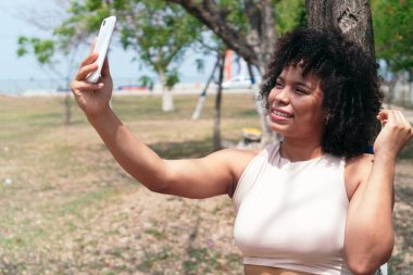 Parktaki Latin kadın telefonunu kullanıyor..