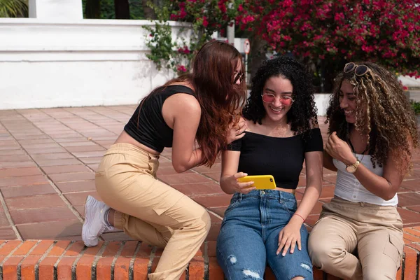 Üç Latin arkadaş dışarıda selfie çekiyorlar.