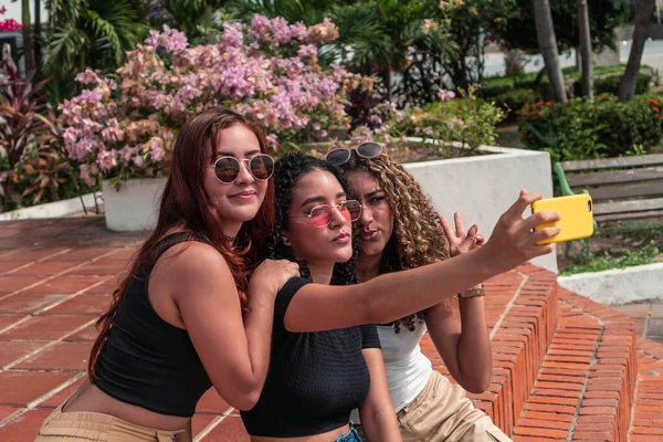 Park 'ta surat yaparken selfie çeken üç genç kız arkadaş.