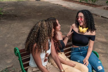 Parkta bir bankta oturan üç Latin arkadaş