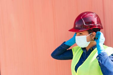 Güvenlik kaskı takan koruyucu maskeli bir endüstri işçisi.