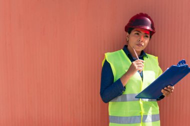 Fabrikada koruyucu yelek giyen Latin bir kadın.