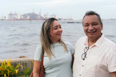 Orta yaşlı çift mutlu bir şekilde gülüyor ve parkta birbirlerine sarılıyorlar..