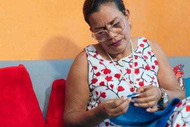 Evde örgü ören olgun bir kadın.