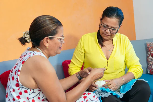 Olgun bir kadın arkadaşına yün örgü örmeyi öğretiyor.