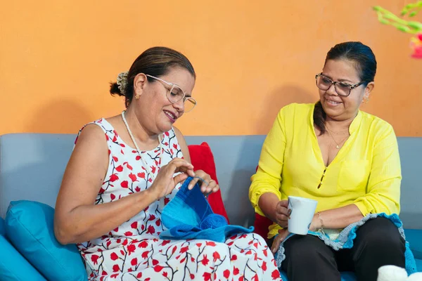 Olgun kadınlar evde örgü örüyor.