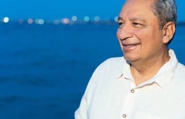 Dışarıda dikilen gülümseyen olgun bir Latin adamın portresi..