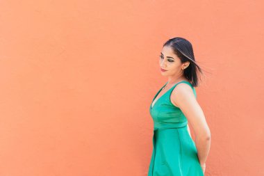 Genç bir kadın kırmızı duvarın önünde yürüyor.