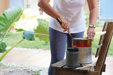 Tanımlanamayan bir kadın eski bir tahta sandalyeyi boyamaya hazırlanıyor..