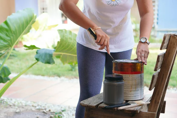 Tanımlanamayan bir kadın eski bir tahta sandalyeyi boyamaya hazırlanıyor..