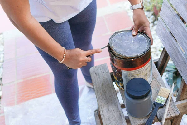 Tanınmayan bir kadın antika sandalyeyi onarmak için boya kutusu açıyor.