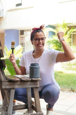 Kadın eski bir sandalyeyi boyuyor ve evinde eğleniyor..