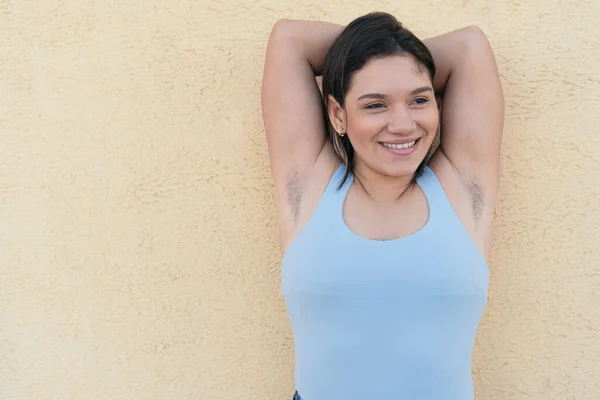 Young and natural woman with unshaved armpits smiling with happiness.