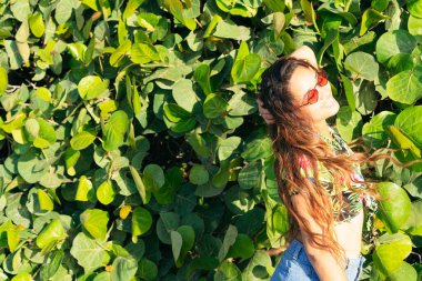 Esmer kadın. Yeşil Yapraklara Karşı Duran Gülümseyen Kadın Park Arkaplanda