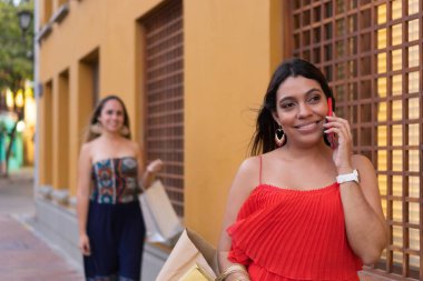 Alışveriş yaptıktan sonra bir kadın sokakta cep telefonuyla konuşuyor.