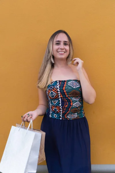 Hermosa Mujer Sonriente Vestido Azul Sosteniendo Bolsas Compras Posando Pared —  Fotos de Stock