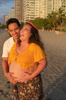 İspanyol adam hamile kadınını kucaklıyor.