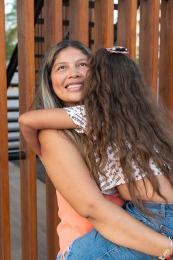 İspanyol anne ve kız parkta neşeyle oynuyorlar.