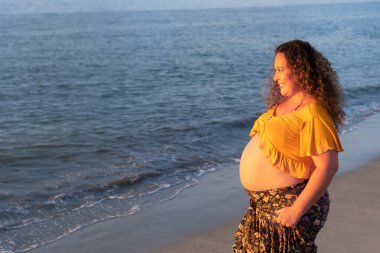Sahilde duran hamile kadın.