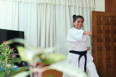 Geleneksel kimono giymiş, evde karate yapan genç bir kız.