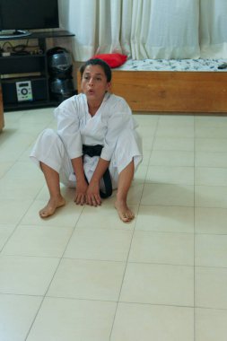 Kimonolu kadın karate eğitiminden önce ısınıyor. Bacaklar için esneme egzersizleri yapıyorlar..