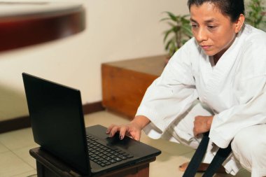 İspanyol kadın evde karate dersi için bilgisayar hazırlıyor.